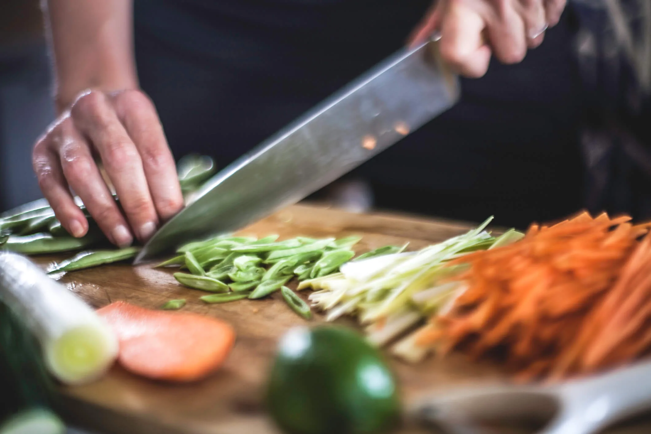 A person cutting up vegetables on a chopping board