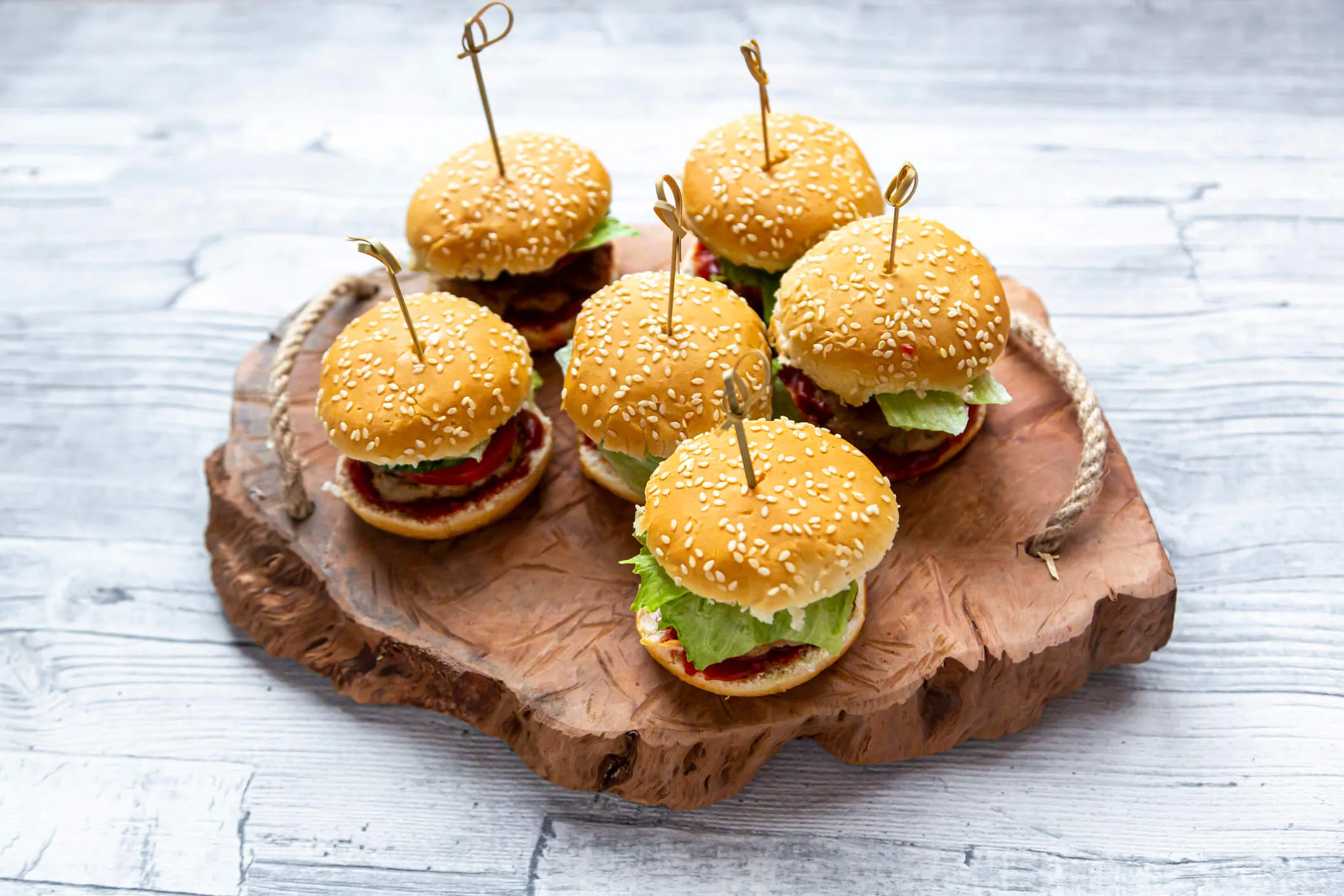 Slider burgers sitting on a wooden serving board