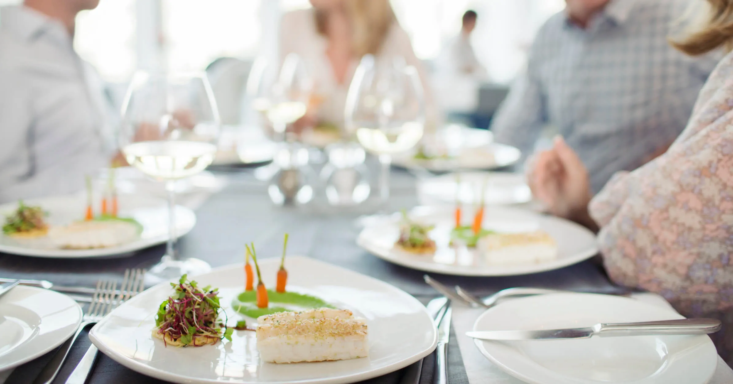 A family eating a fancy fish dinner with glasses of white wine