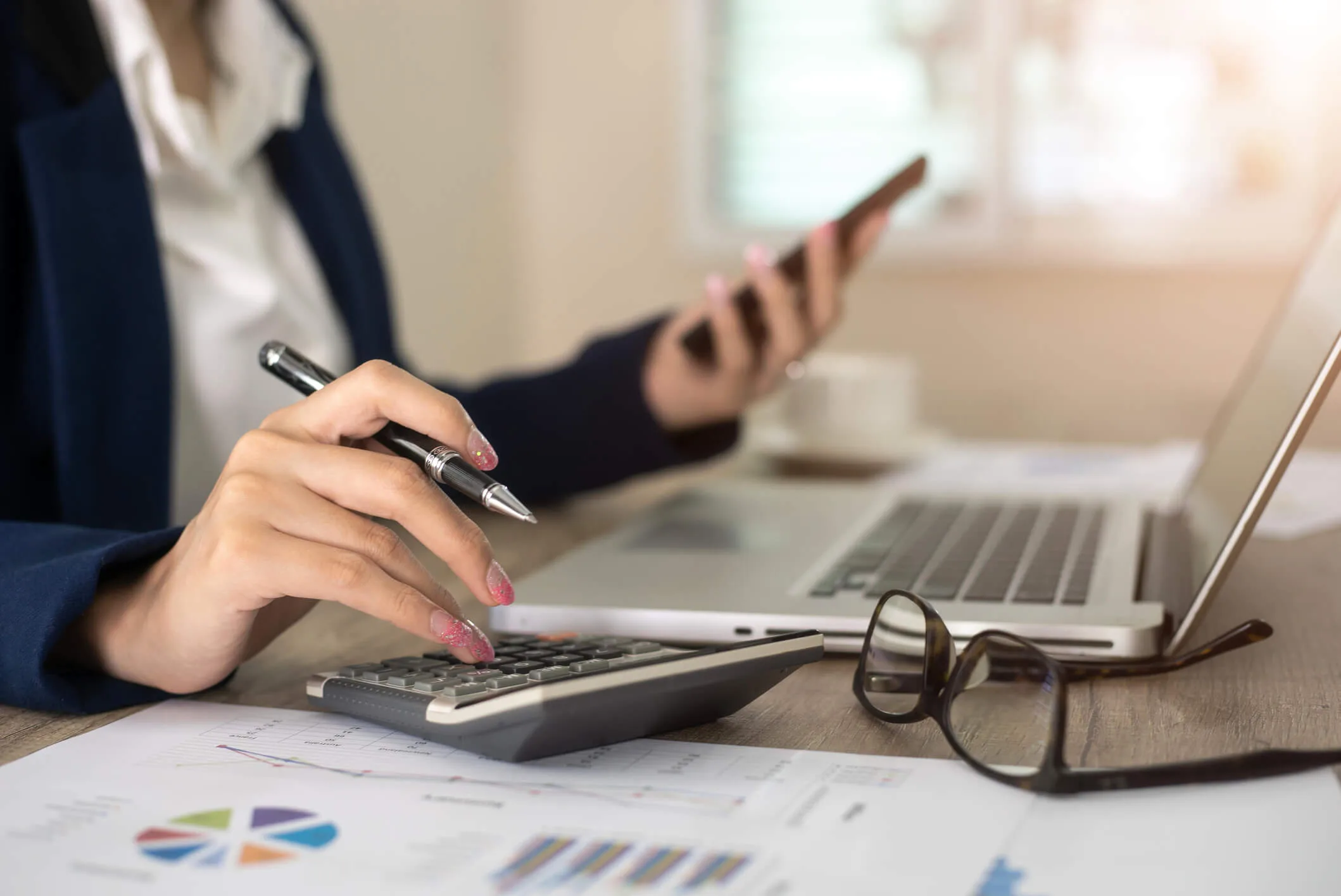 A woman doing finances on the computer while typing on a calculator
