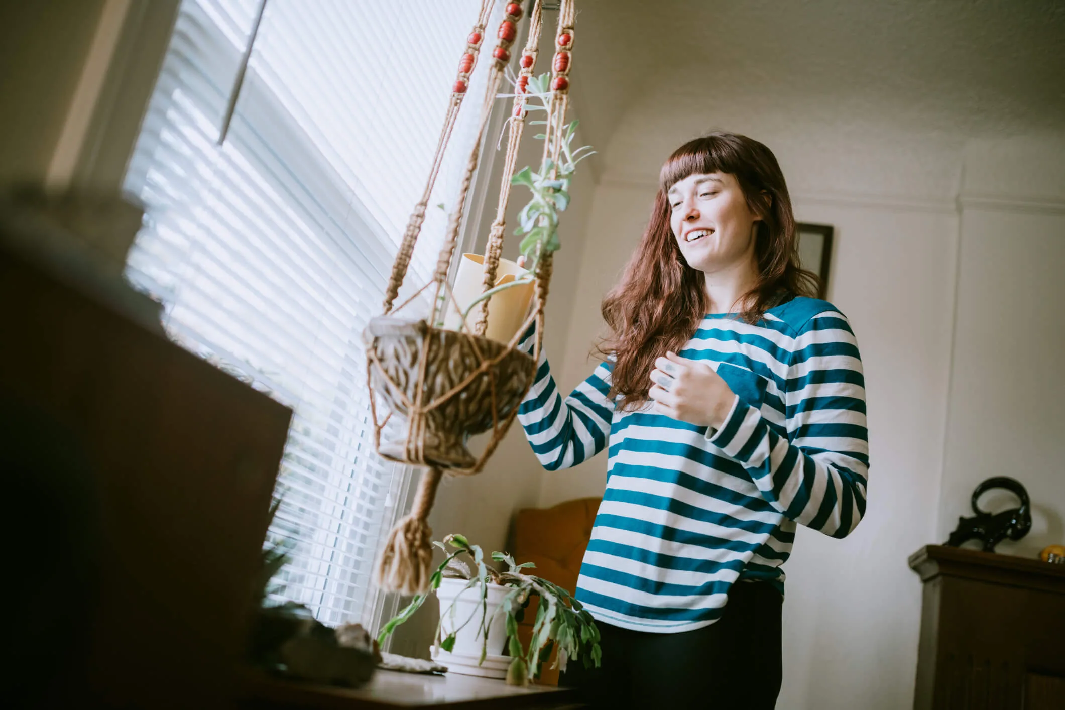 A woman watering a plant in a hanging pot