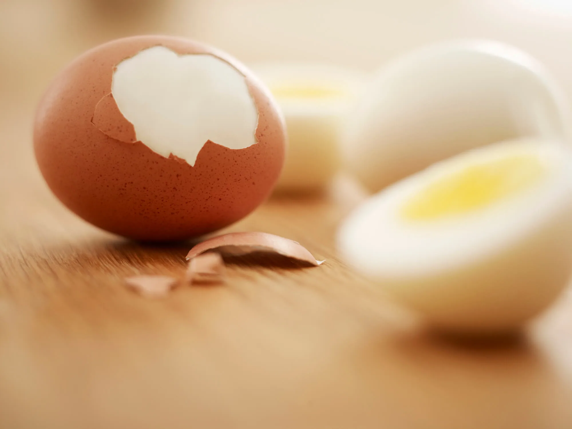 A cracked hard boiled egg on a wooden chopping board