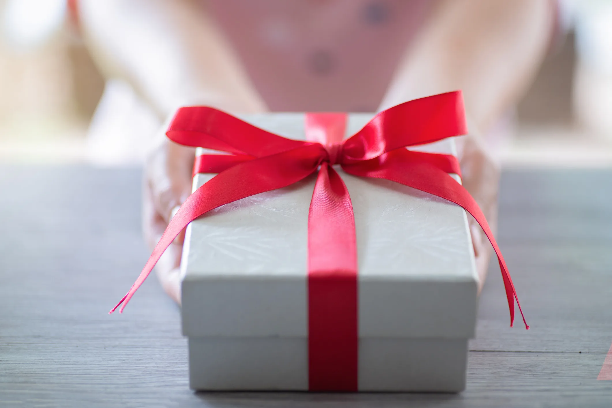 A white box wrapped in a red ribbonn