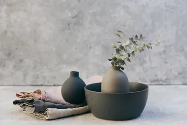 Stone vases with a flower and tea towels against a grey stone background