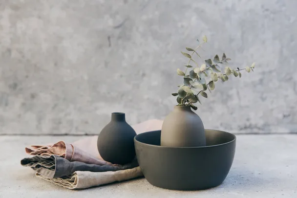 Stone vases with a flower and tea towels against a grey stone background