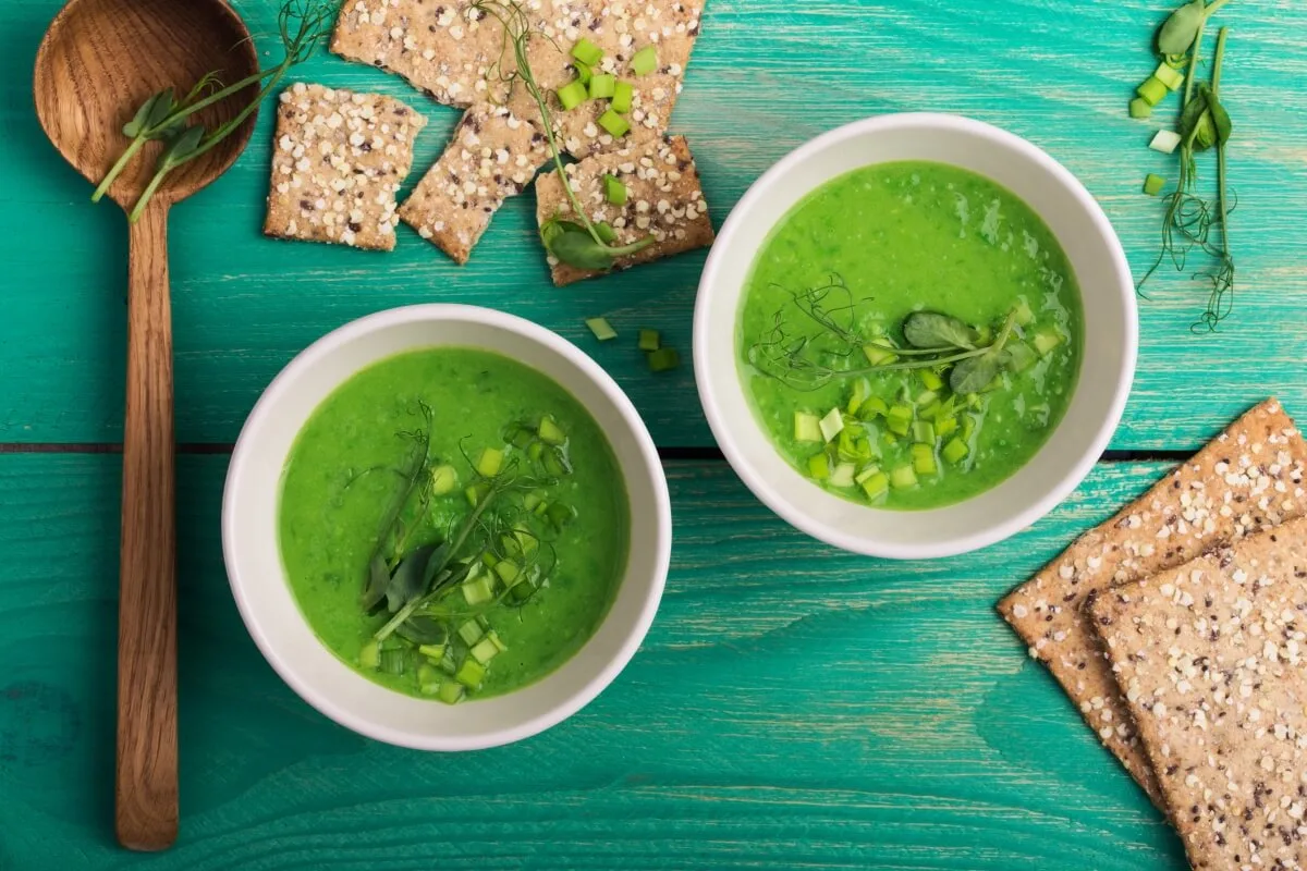 An overhead shot of green pea cream soup with sprouts