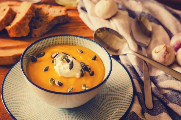A bowl of pumpkin soup with cream and pumpkin seeds