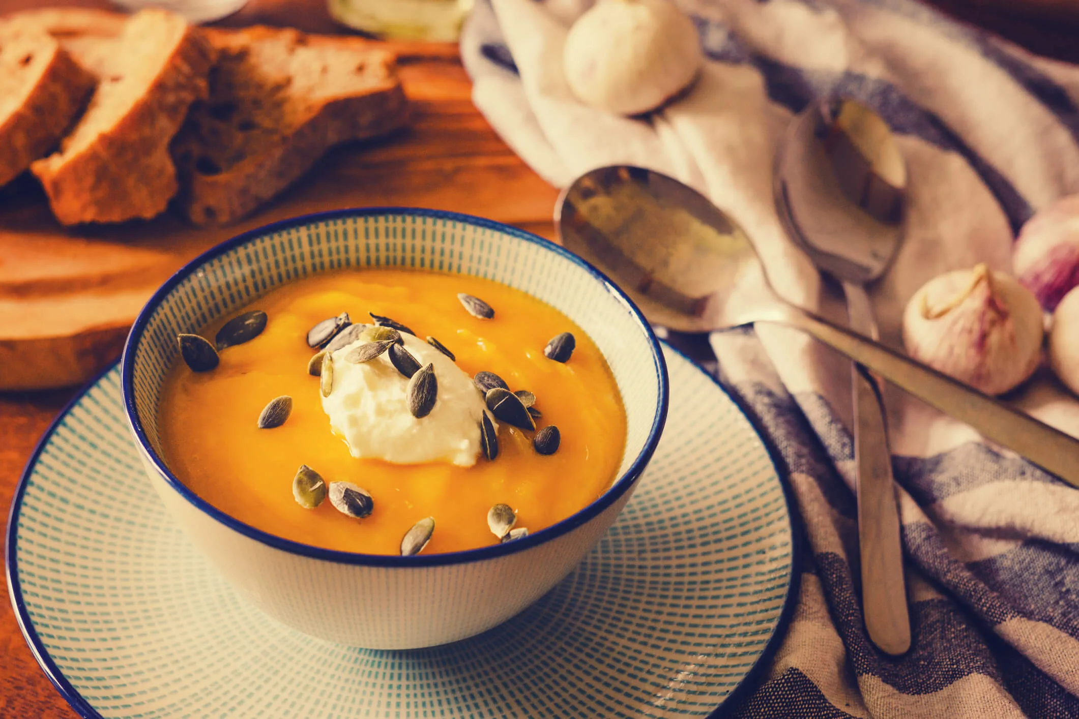 A bowl of pumpkin soup with cream and pumpkin seeds
