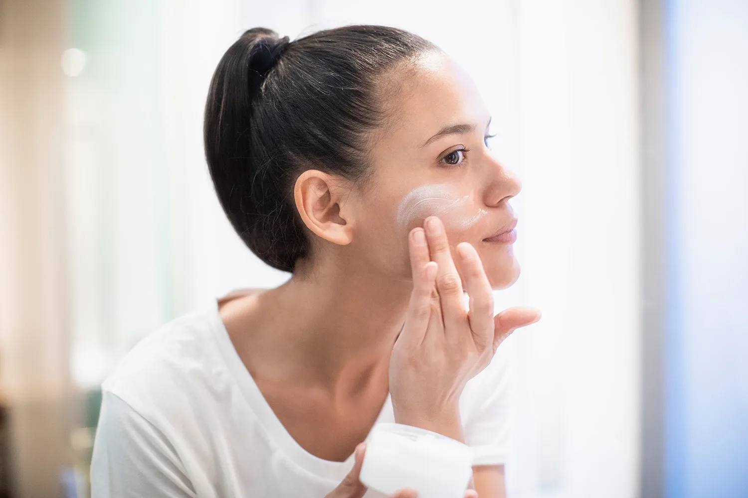 woman applying skincare products to face