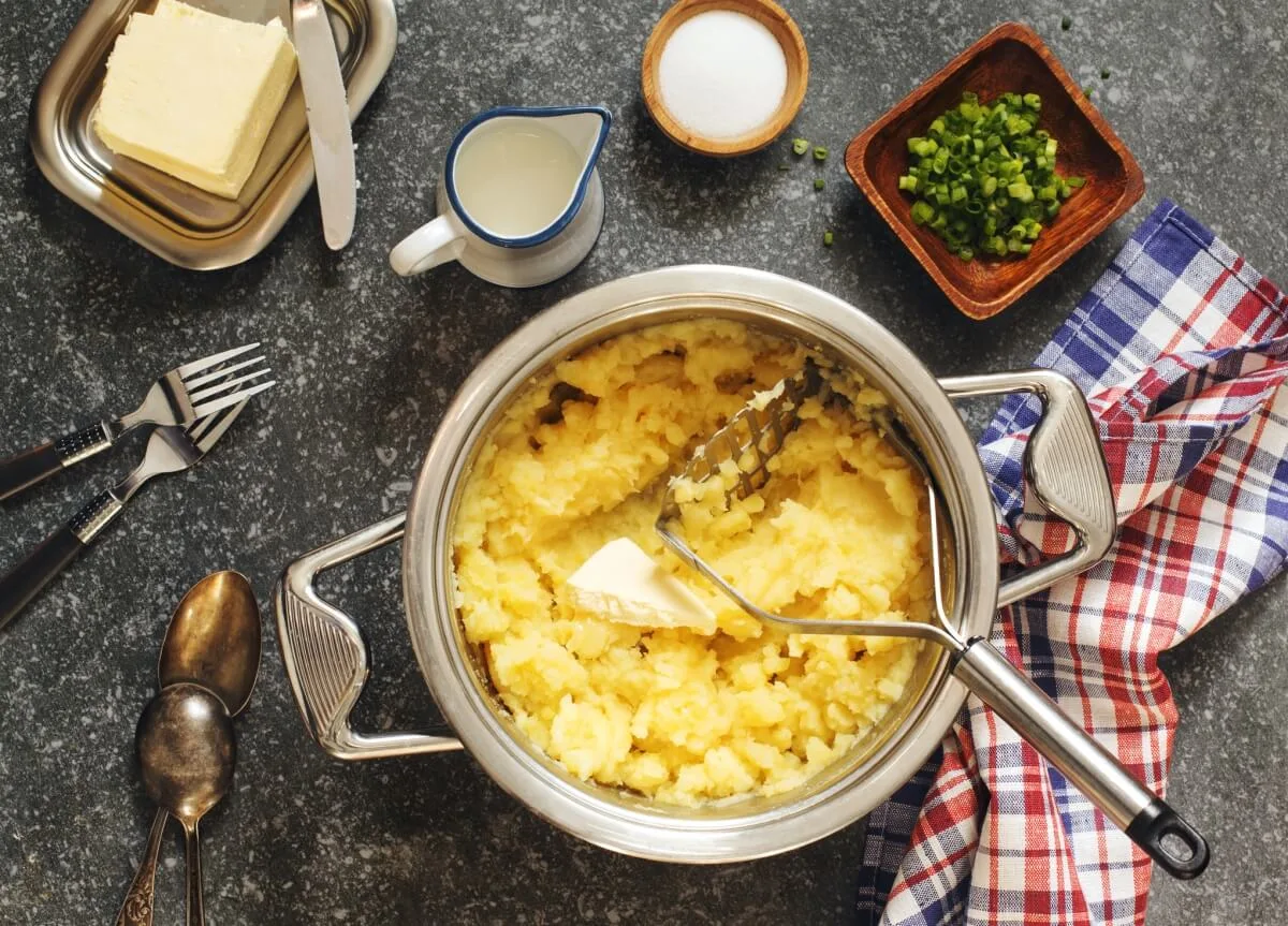 A stainless steel cooking pot with mashed potato and butter