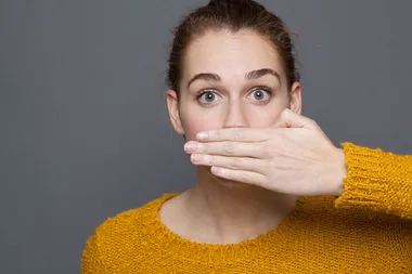 woman holding hand over mouth