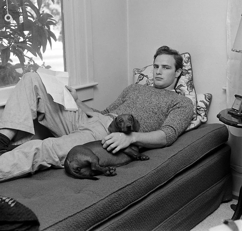 Marlon Brando lying on a couch with his dachshund
