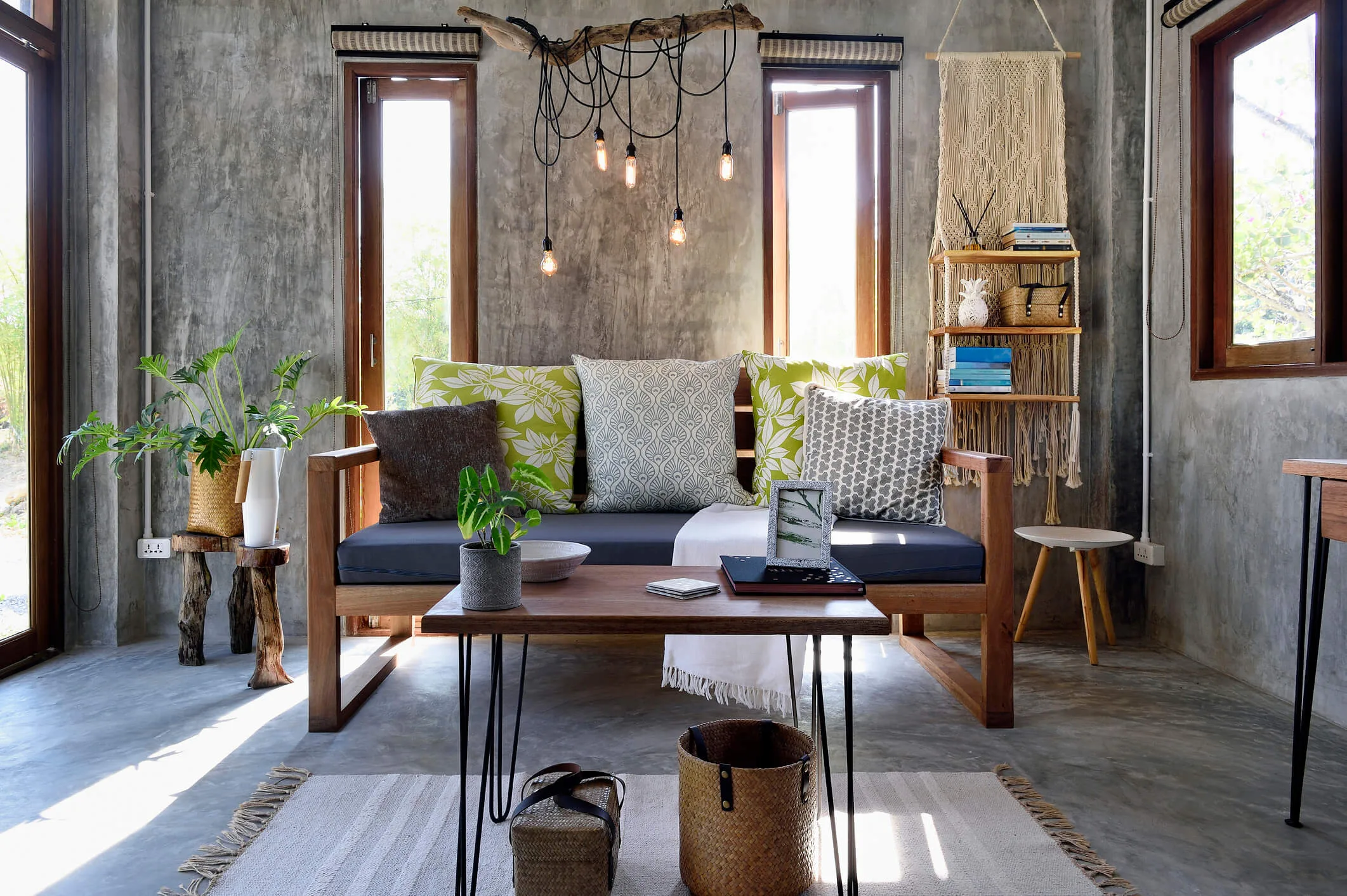A small sunroom with a couch and coffee table, with concrete floor and walls