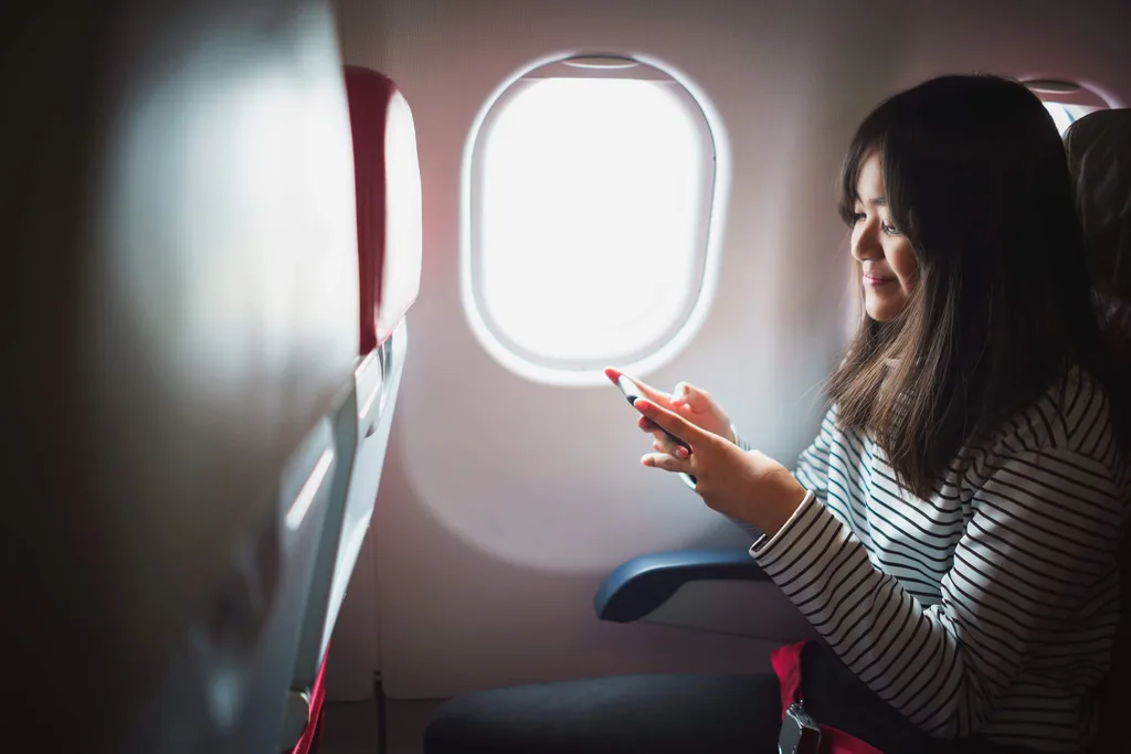 A woman on her phone while seated on a plane