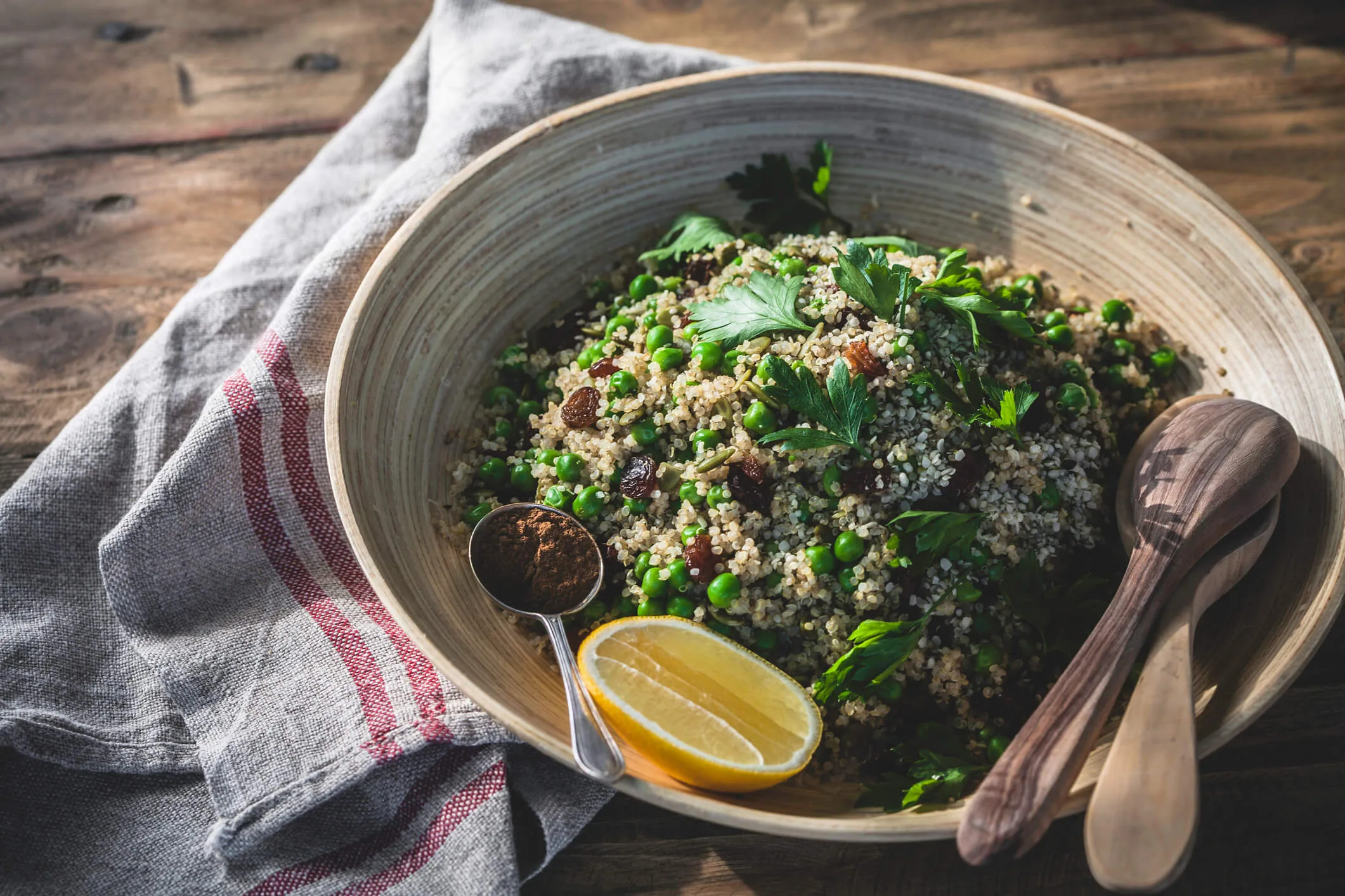 A bowl of quinoa with a wooden bowl and utensils