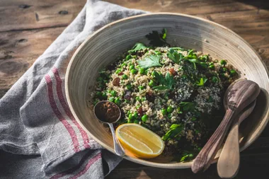 A bowl of quinoa with a wooden bowl and utensils