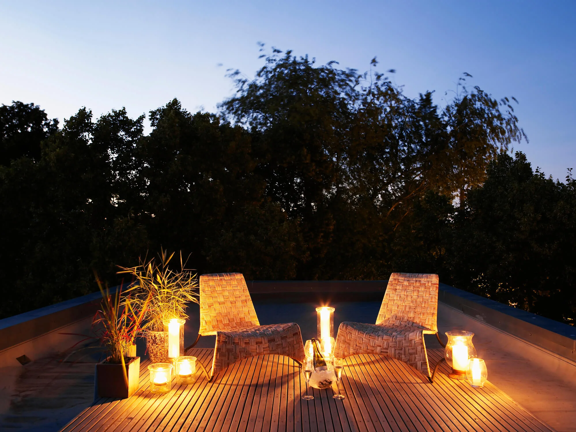 A rooftop deck lit by candles at dusk