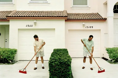 two men sweeping driveways