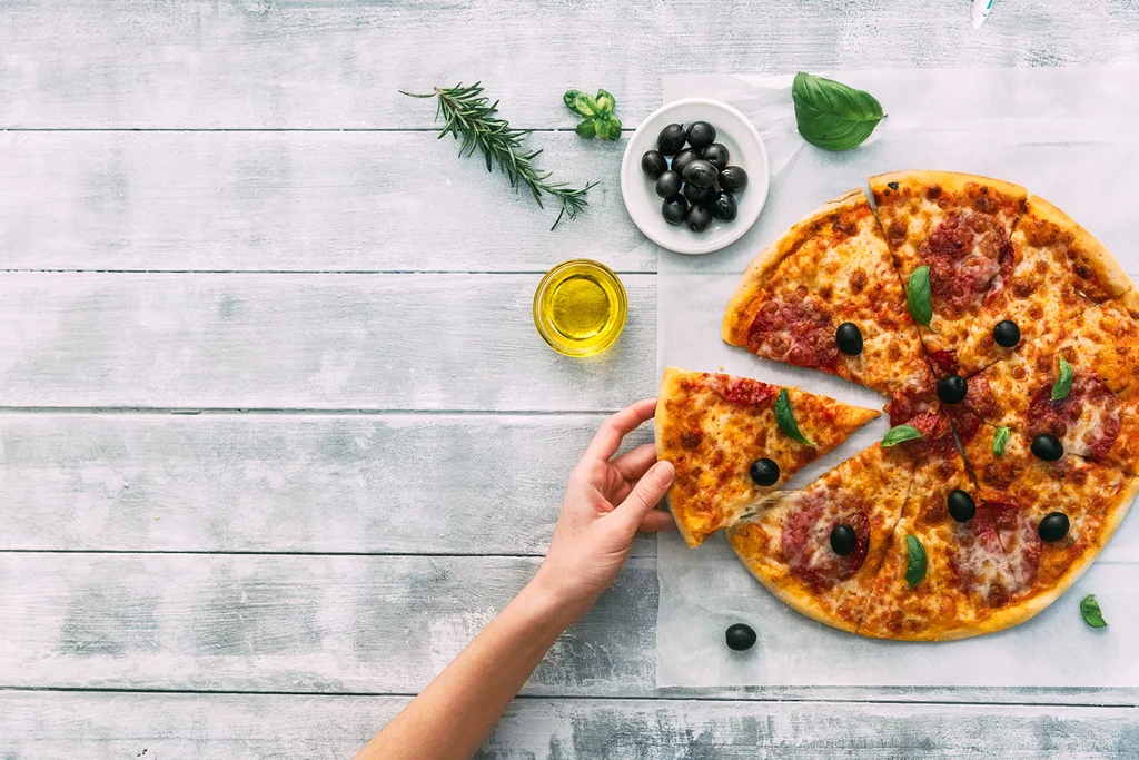 Hand taking pizza slice