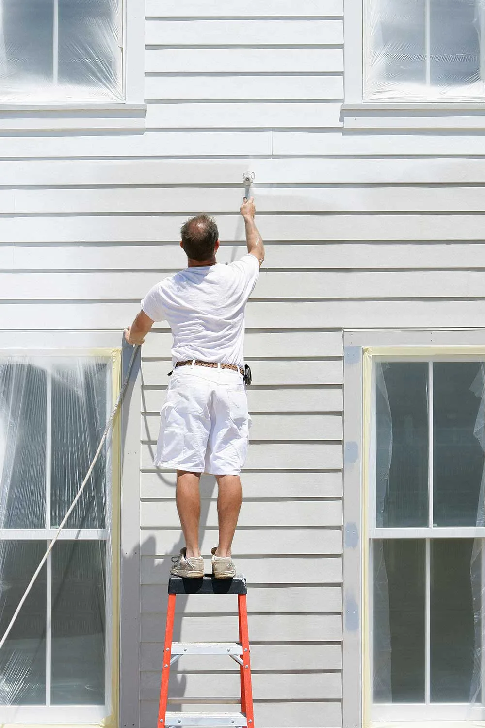 Man painting exterior of house