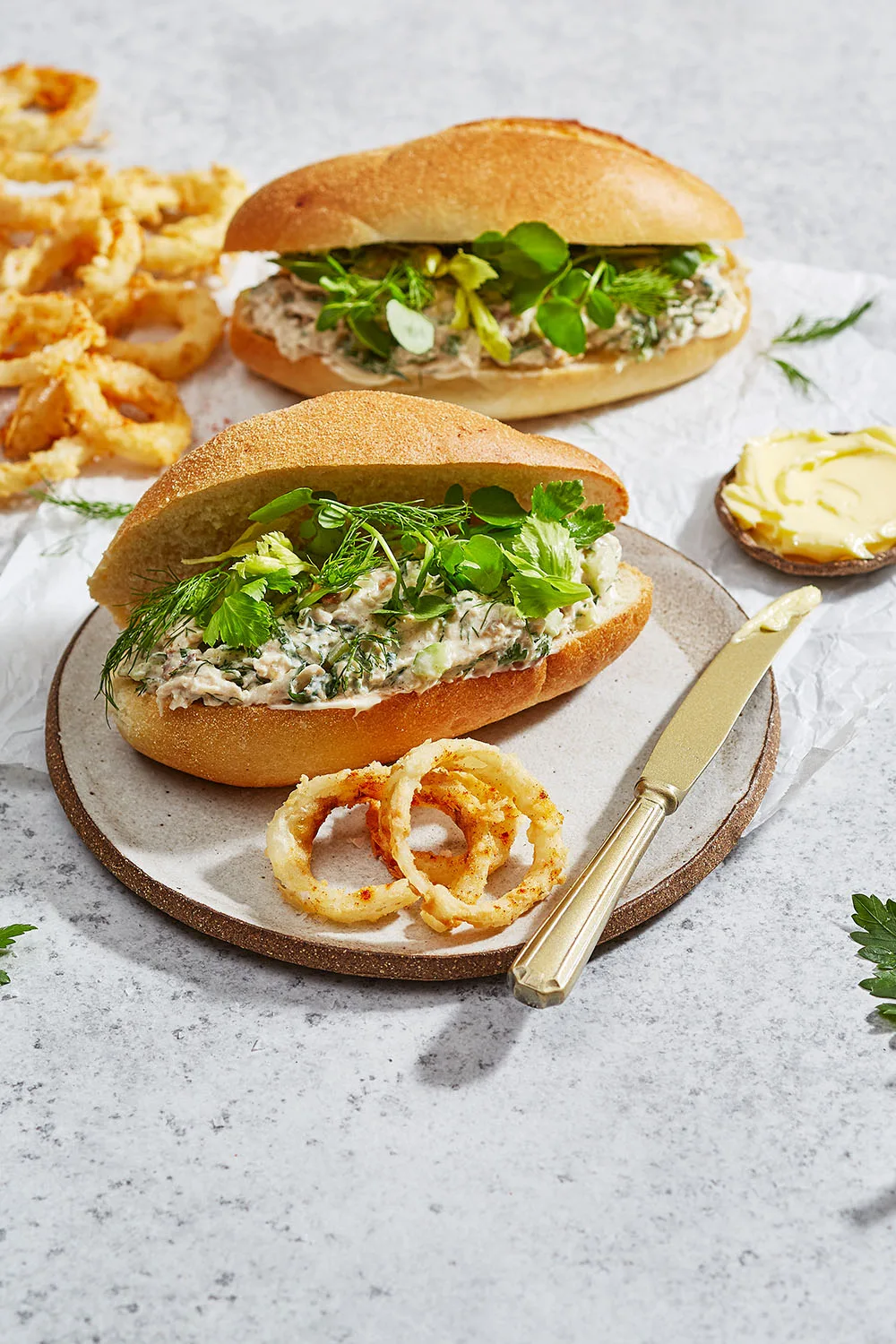 open faced ciabatta roll made with leftover roast chicken and herbs on top. onion rings on the side stacked together