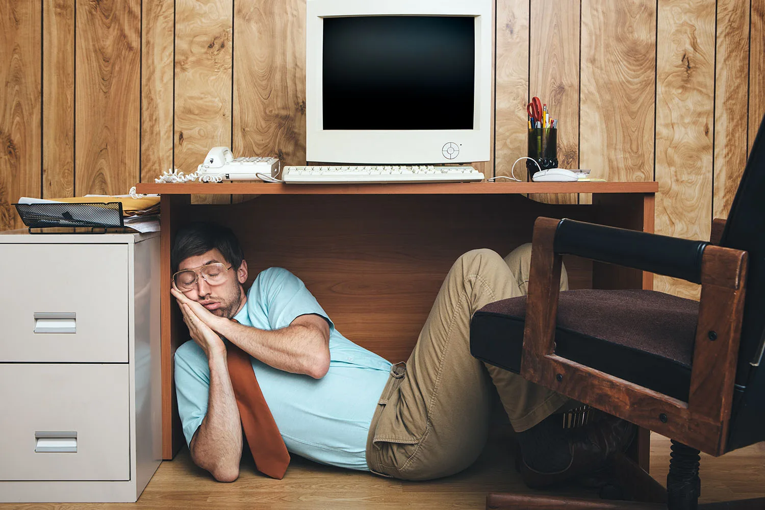 man sleeping under desk