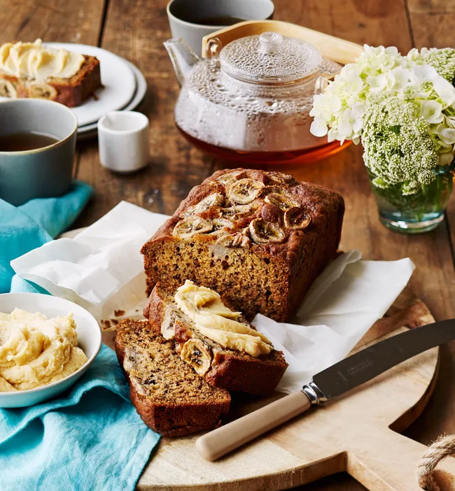 Banana bread with miso maple butter with two cut slices, one with butter on it with blue cloth underneath.