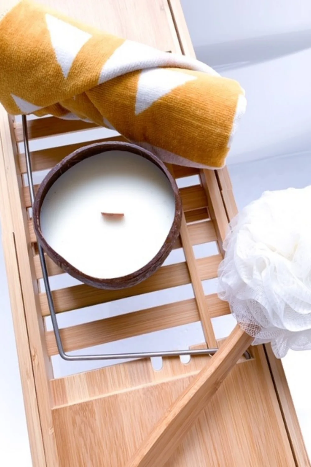Close up of bathtub rack with candle and towel on it