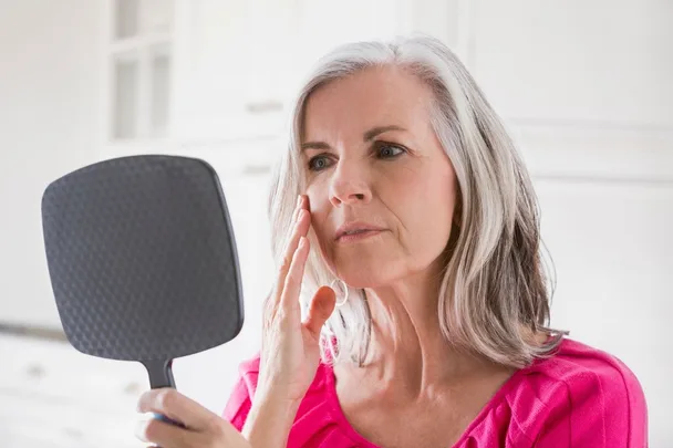 woman looking at face in mirror
