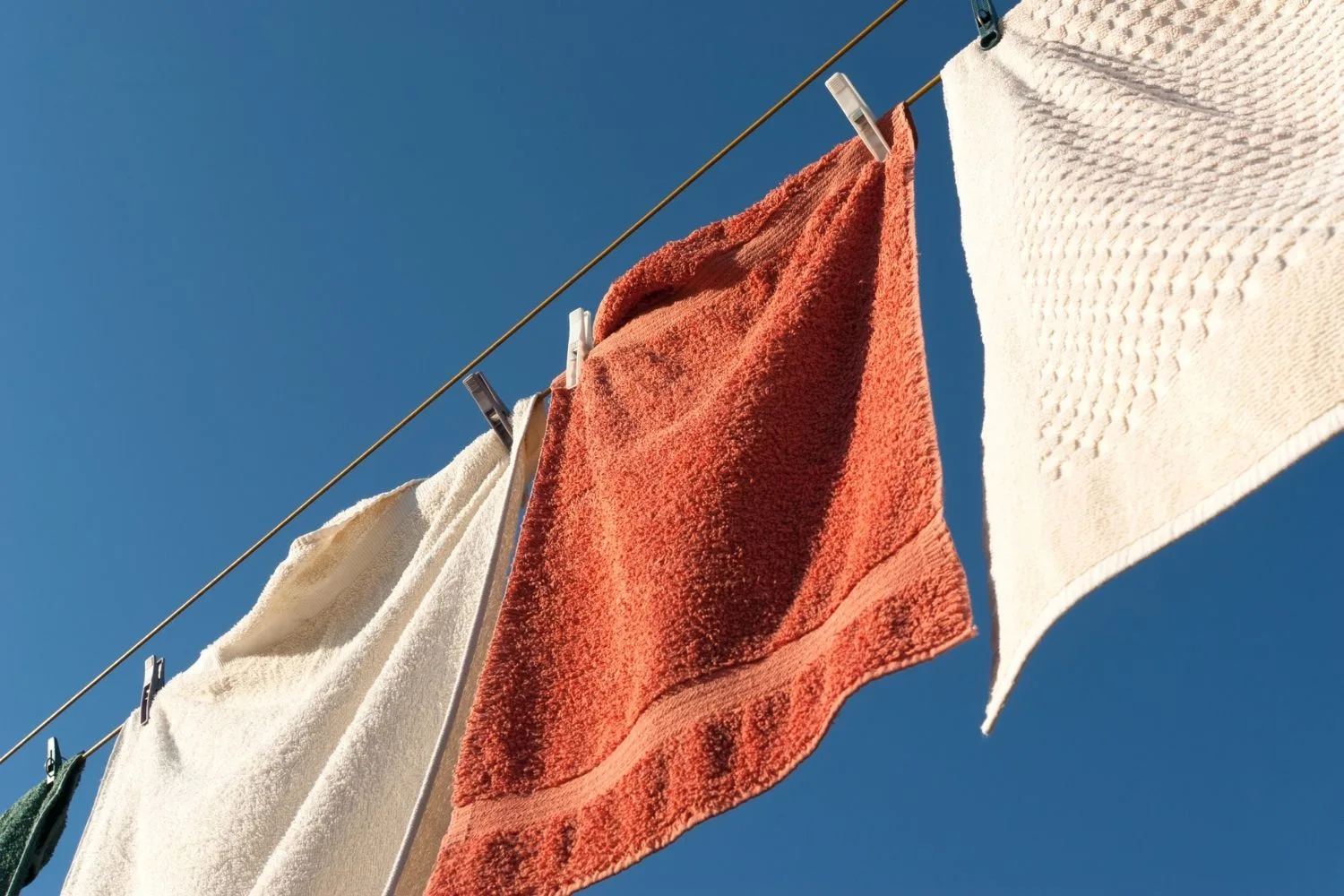 Hanging washed towels outside in sunny weather can help them feel fresh and clean.
