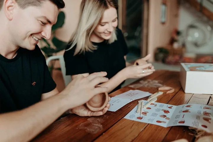 Man and woman sitting next to each other making pottery