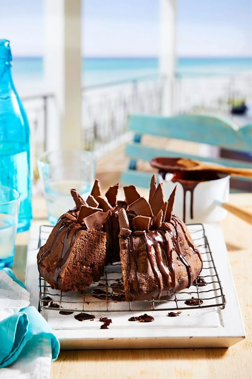 choc cake on cooling rack with chocolate dripping down sides and shards of chocolate 