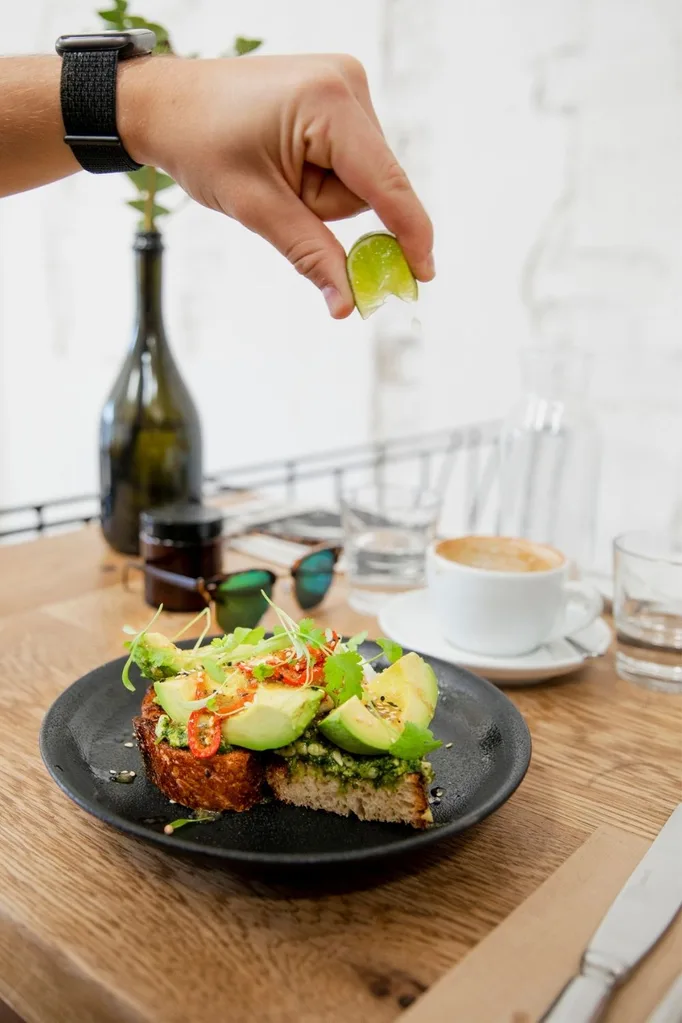 Squeezing lime onto avocado on toast
