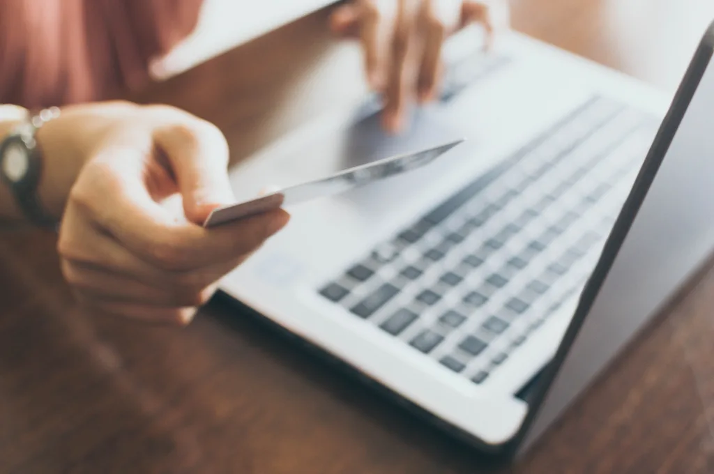 Person on laptop holding credit card
