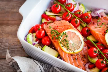 Salmon filets on a bed of vegies in a white baking dish