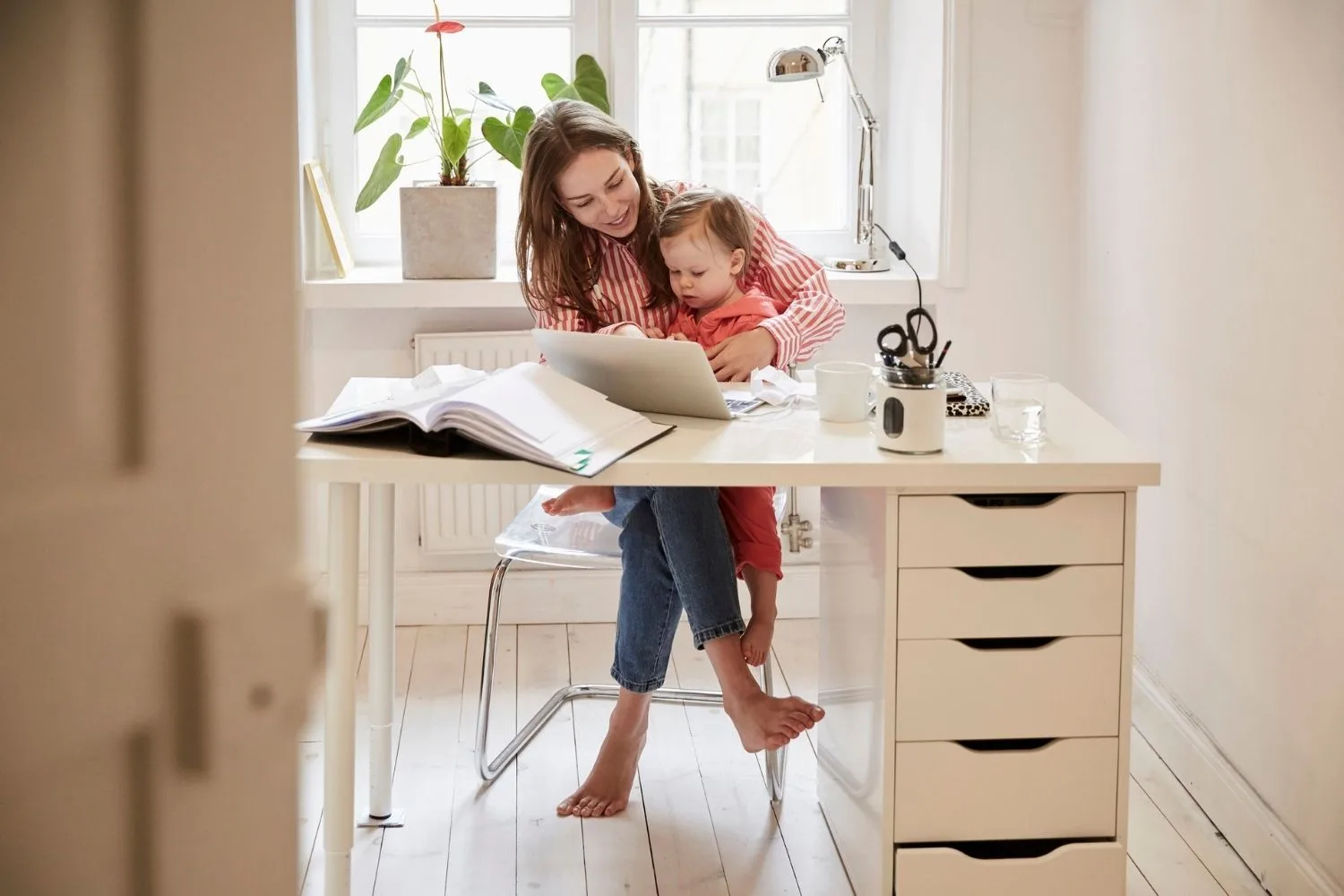 Woman with baby sitting at home office desk
