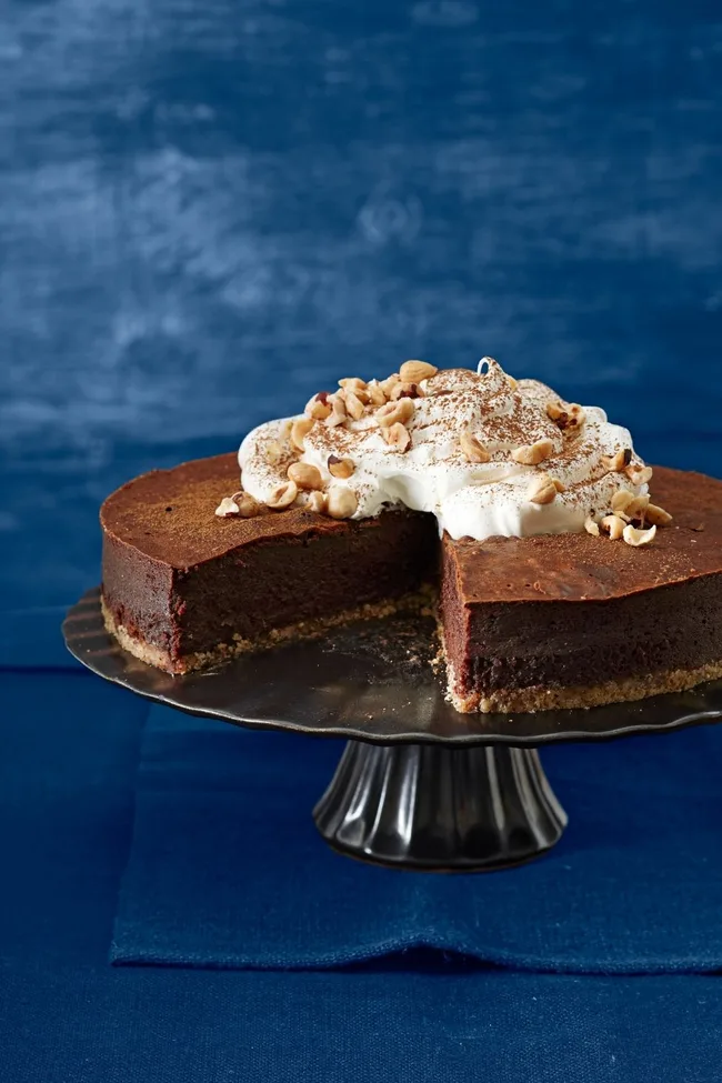choc cake on black cake stand with cream and shaved chocolate on top