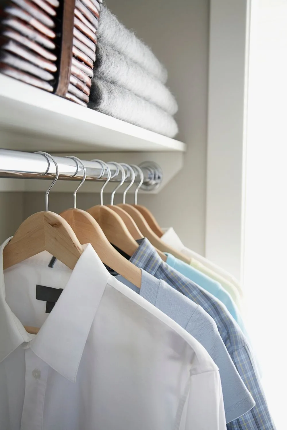 Shirts hanging on wooden coat hangers in wardrobe