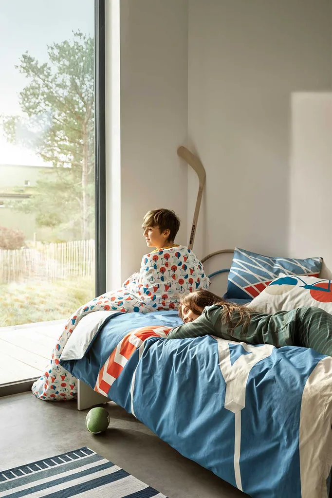 Boy and girl sitting on bed with IKEA linen