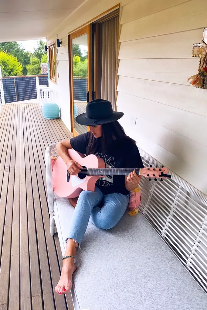 Megan Gale playing guitar on the deck of her holiday home in Daylesford, VIC