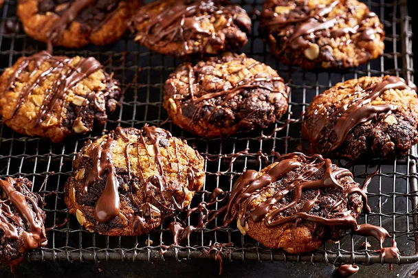 close up of anzac biscuits that are drizzled with orange and dark chocolate on a cooling tray