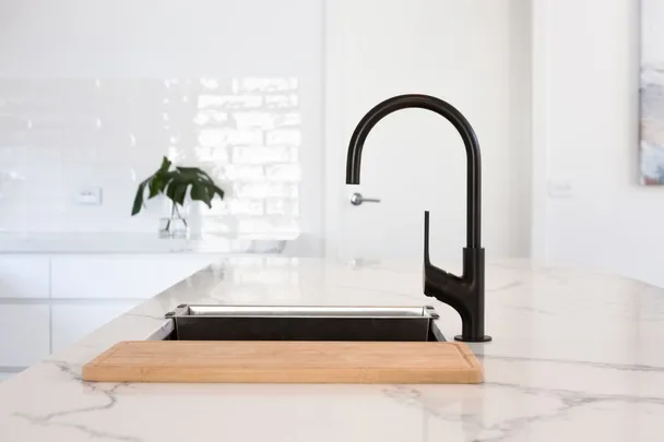 Marble kitchen bench with timber chopping board and black tap