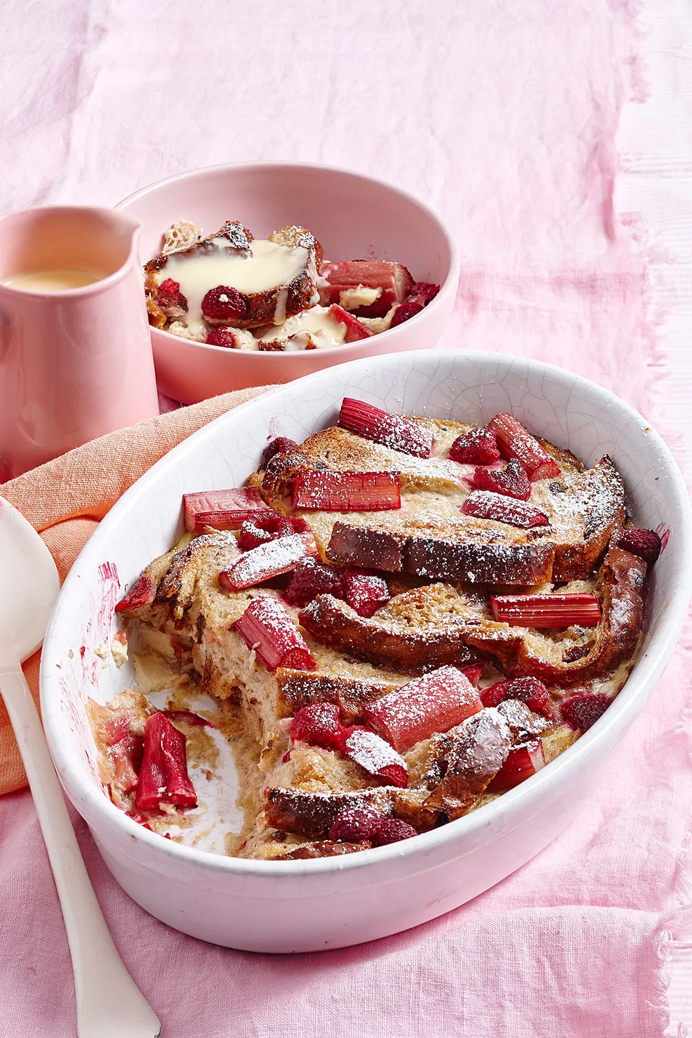 white pie dish with bread and butter pudding and rhubarb pieces toasted on top