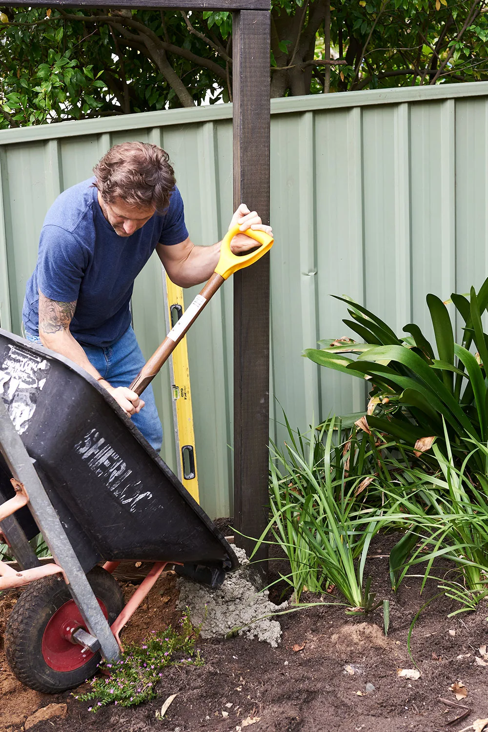 Charlie Albone mixing pouring concrete into holes