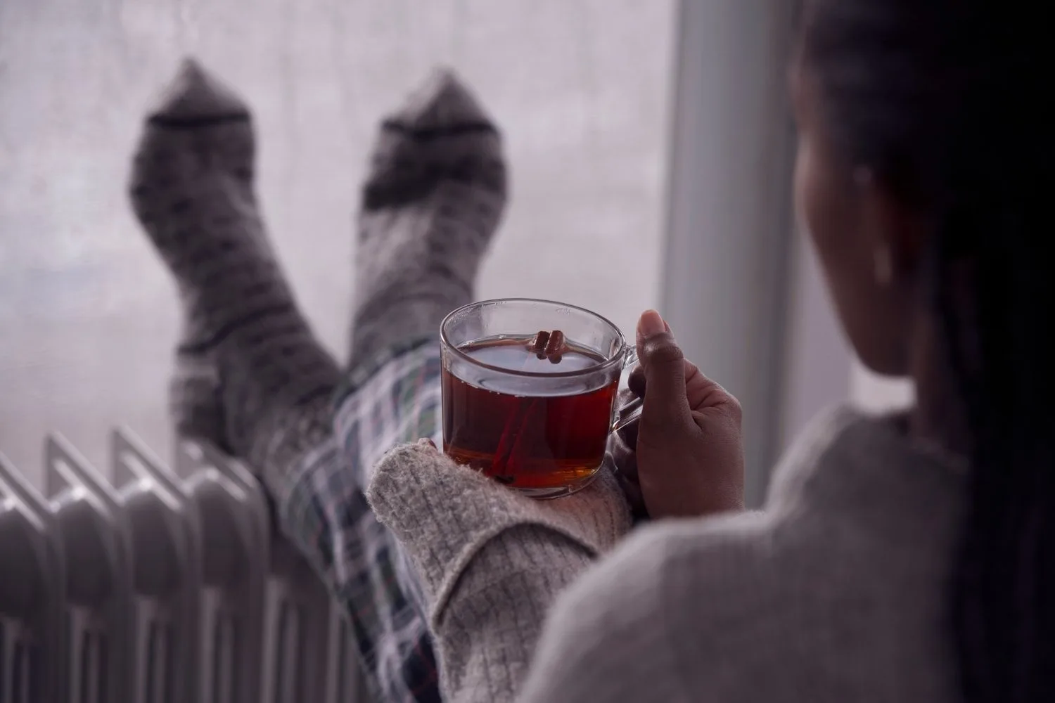 woman with tea and feet on heater
