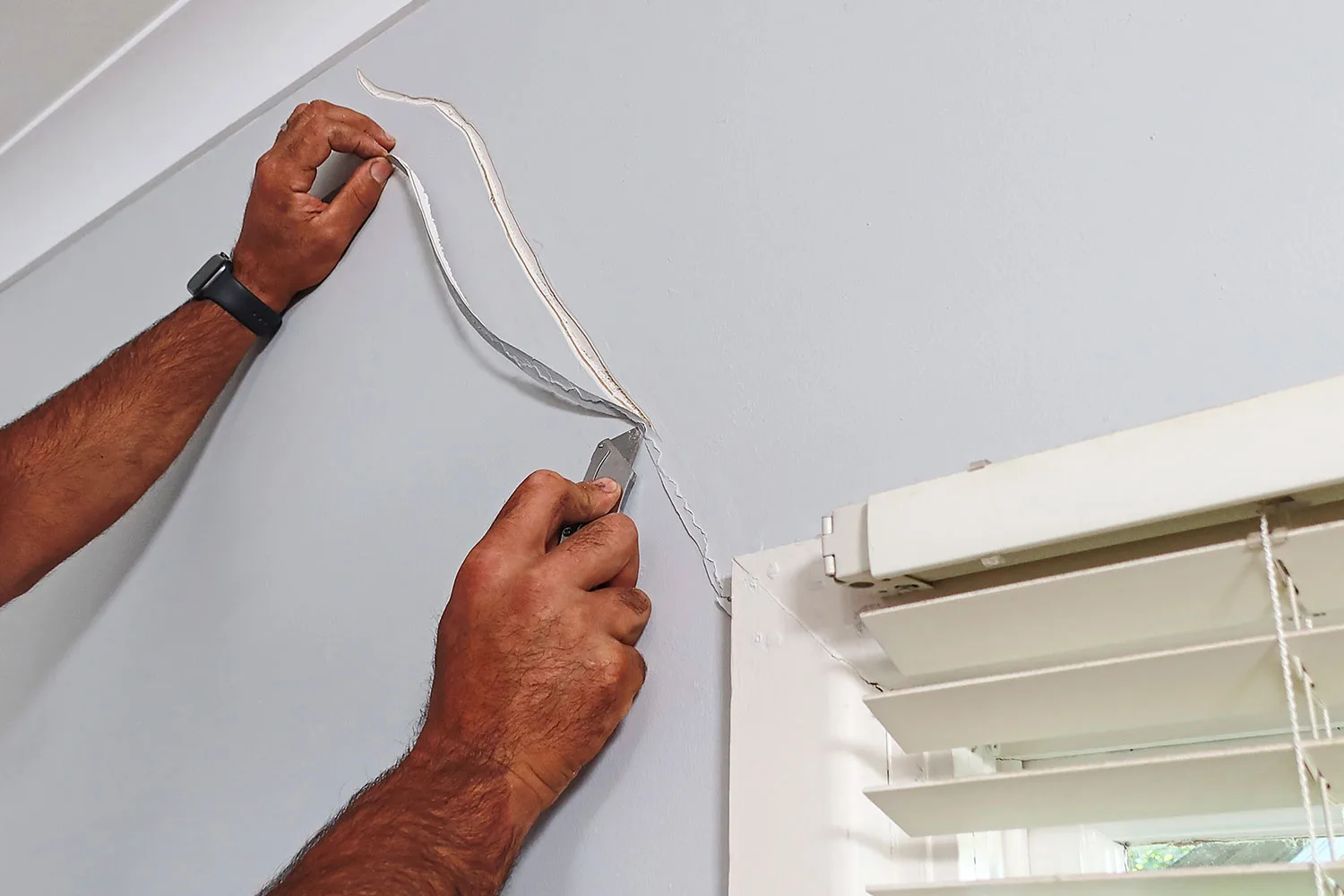 Cut out plasterboard around crack