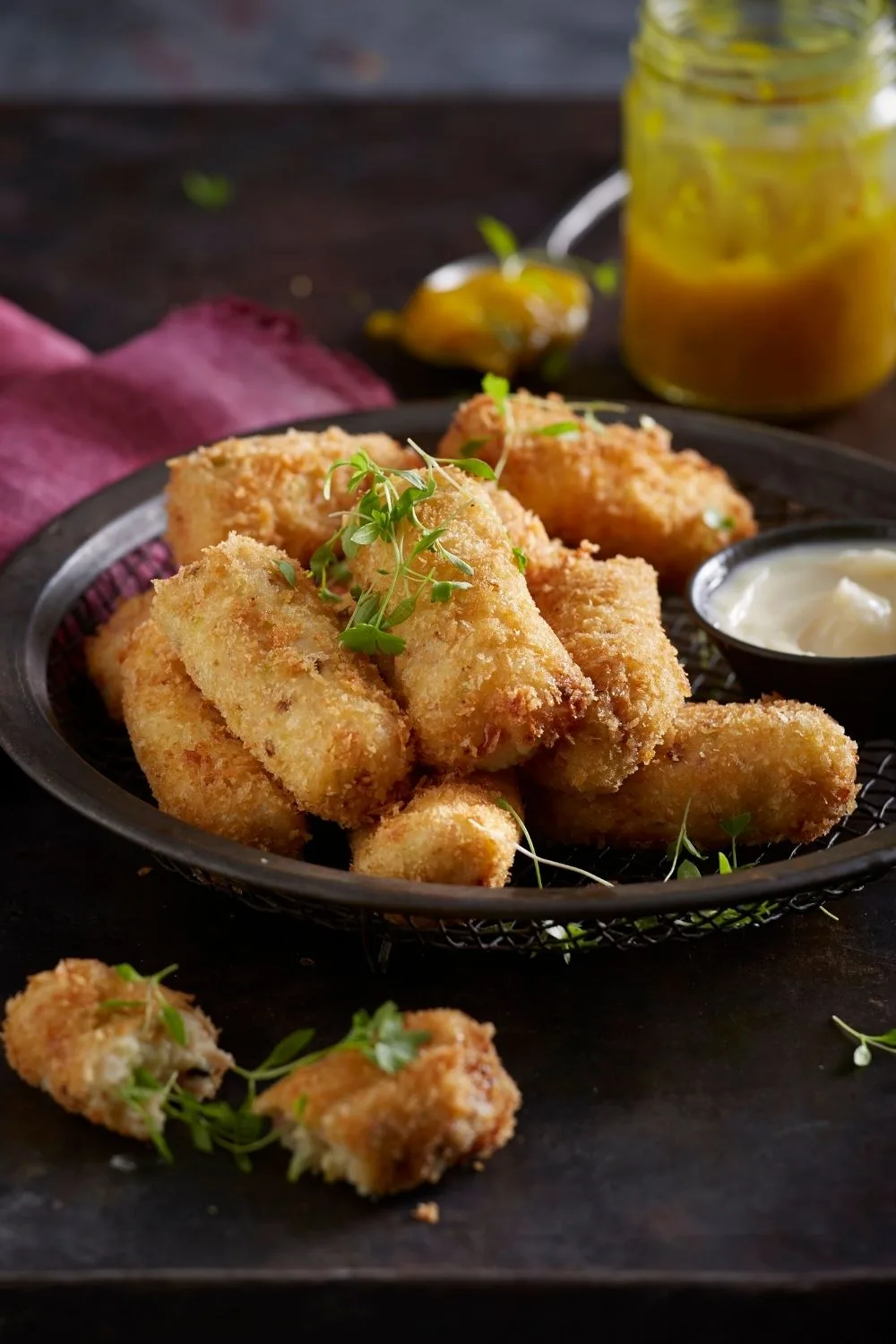 cheese croquettes with herbs garnishing the top and sauce on the side