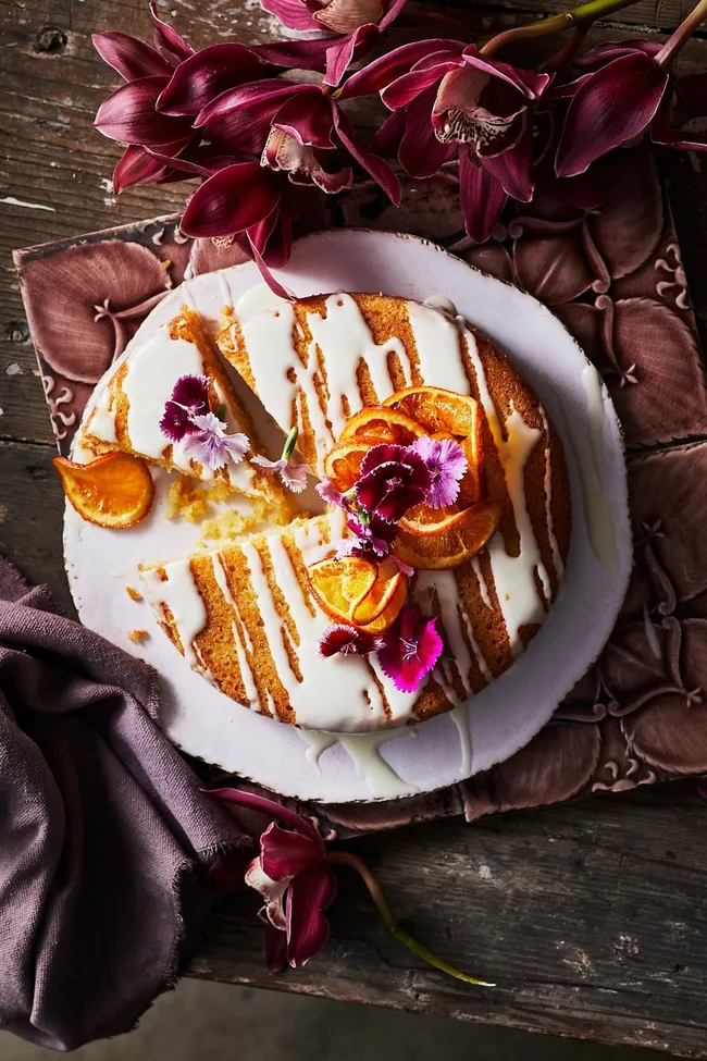 orange drizzle cake with white icing and rose on top