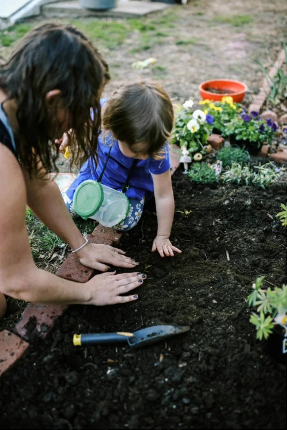 A mother and her child planting pansies and bare root strawberries