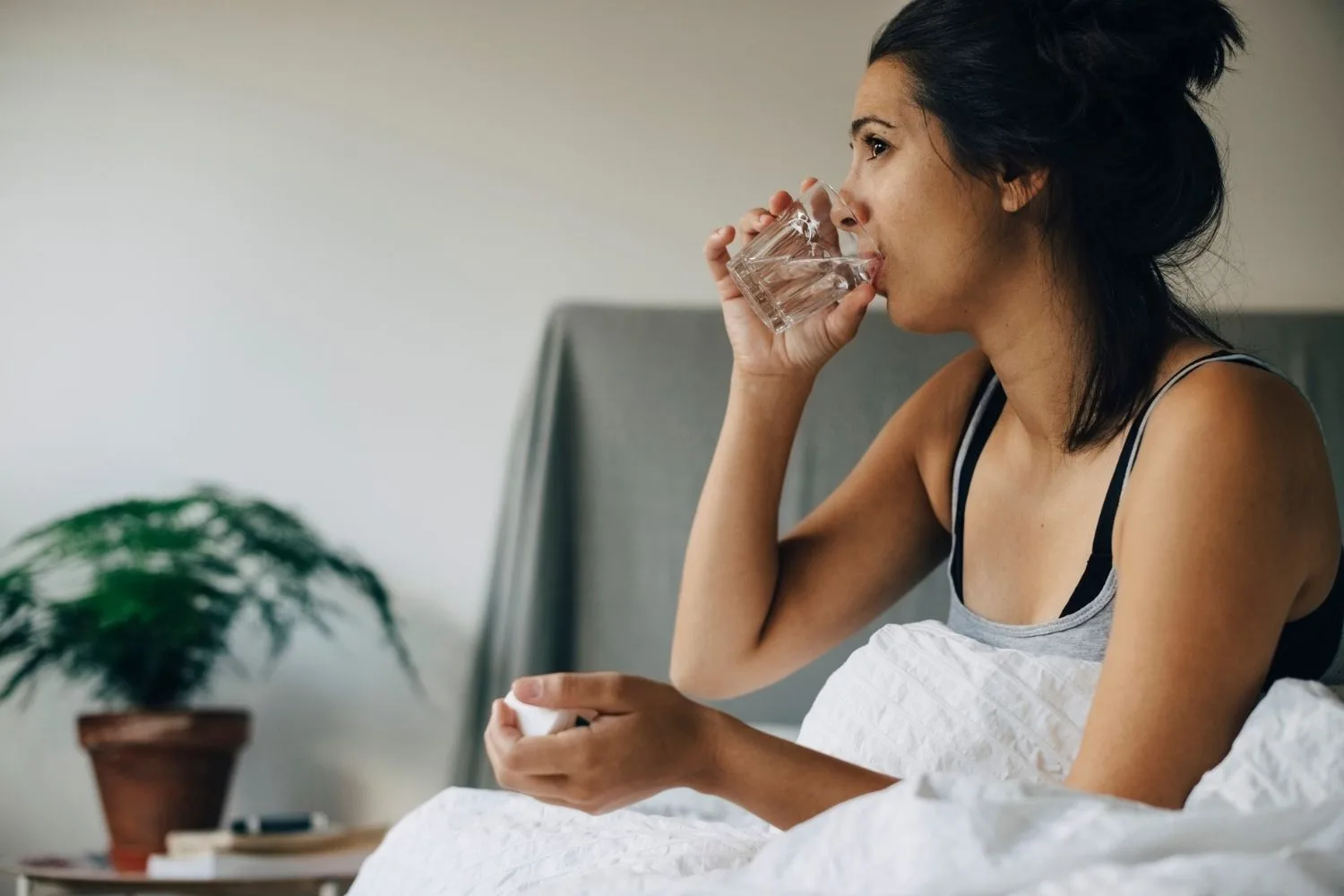 Woman taking pill in bed.
